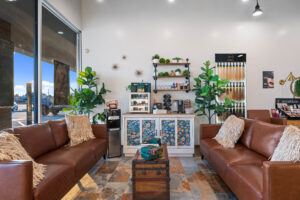 - The Color Bar, TX A waiting area in the hair salon with two brown leather sofas, a wooden trunk table, plants, and a cabinet with drinks and snacks on a tiled floor. Large windows bring in natural light while you await your haircut or hair color appointment. - The Color Bar, TX