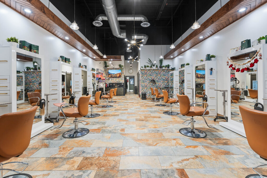 - The Color Bar, TX A modern hair salon interior with brown styling chairs, mirrors, and a tiled floor. The space is brightly lit with overhead lights and decorated with plants, wall art, and features dedicated areas for balayage and hair color services. - The Color Bar, TX