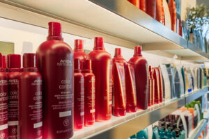 - The Color Bar, TX Shelves display various Aveda hair care products, including multiple sizes of red Color Control shampoo bottles and tubes, perfect for maintaining vibrant hair color or highlights, all arranged in a well-lit store setting ideal for any hair stylist. - The Color Bar, TX