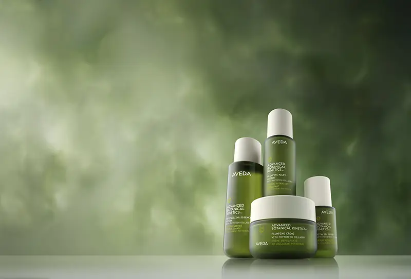 - The Color Bar, TX Four green Aveda skincare products are arranged on a smooth surface with a blurred green background. - The Color Bar, TX
